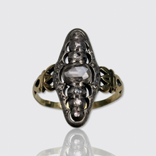 Load image into Gallery viewer, An antique ring featuring a central rose-cut diamond surrounded by smaller diamonds, set in a two-tone metal with a dark silver-toned center and a gold-toned band, shown on a light gray background with a soft reflection below.